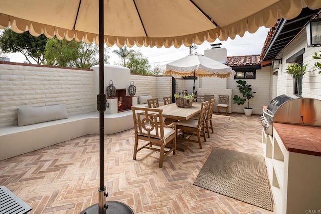 view of patio with outdoor dining area, an outdoor kitchen, and fence