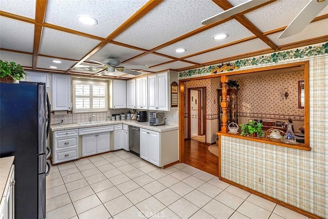 kitchen featuring coffered ceiling, wallpapered walls, ceiling fan, white cabinets, and appliances with stainless steel finishes