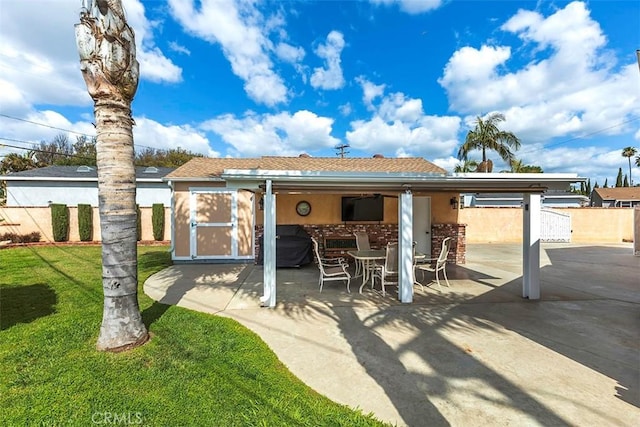 rear view of property with a patio area, an attached carport, stucco siding, fence, and a lawn