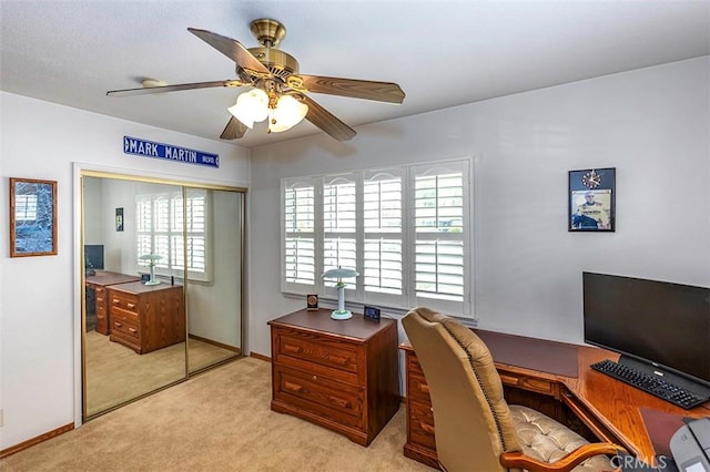 office featuring baseboards, light colored carpet, and ceiling fan