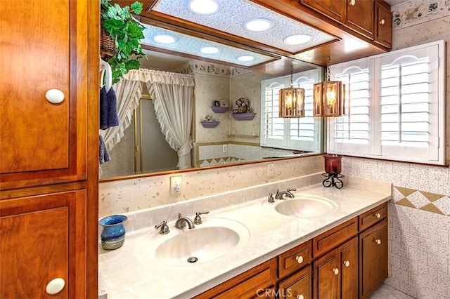 bathroom featuring double vanity, wallpapered walls, and a sink