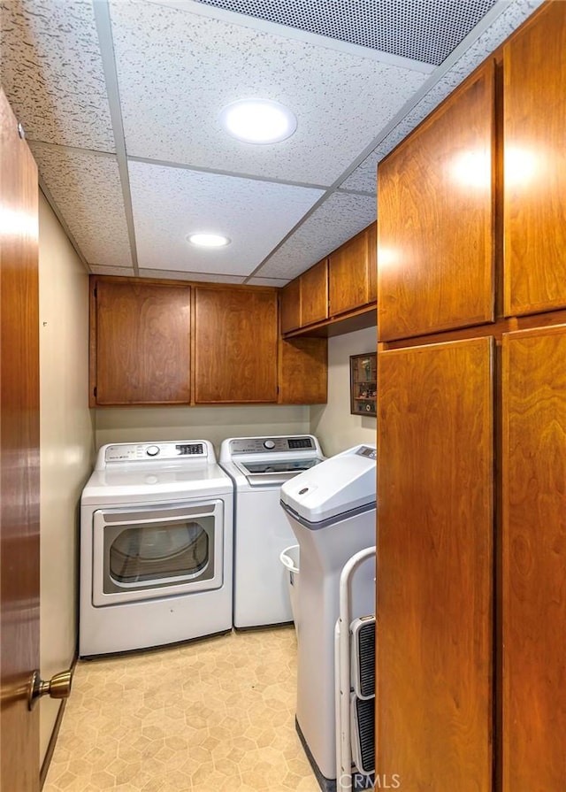 laundry room with washing machine and clothes dryer, cabinet space, and light floors