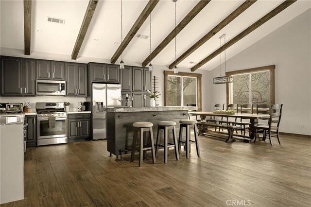 1207 Grass Valley Rd, Lake Arrowhead, CA 92352 - kitchen featuring stainless steel appliances, beamed ceiling, a breakfast bar area, light countertops, and dark wood-type flooring