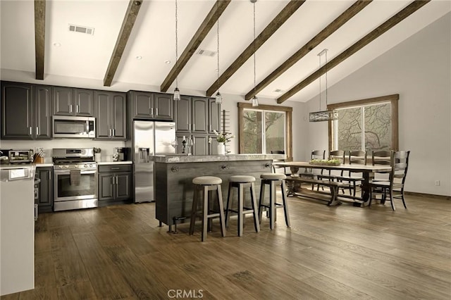 1207 Grass Valley Rd, Lake Arrowhead, CA 92352 - kitchen with appliances with stainless steel finishes, beamed ceiling, a breakfast bar area, light countertops, and dark wood-type flooring