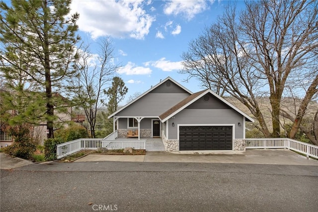 1207 Grass Valley Rd, Lake Arrowhead, CA 92352 - view of front facade with covered porch, stone siding, an attached garage, and driveway