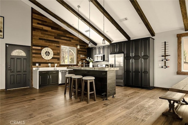 1207 Grass Valley Rd, Lake Arrowhead, CA 92352 - kitchen with stainless steel appliances, a center island, beamed ceiling, wood finished floors, and a breakfast bar