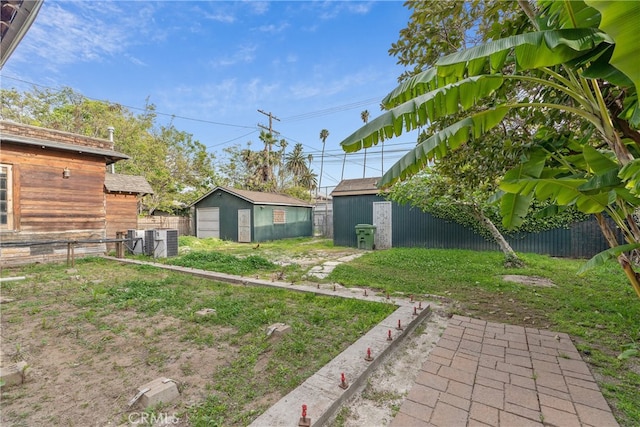 2280 W 24th St, Los Angeles, CA 90018 - view of yard with an outdoor structure, a detached garage, fence, and central AC