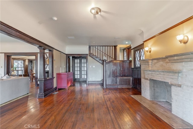 2280 W 24th St, Los Angeles, CA 90018 - unfurnished living room with decorative columns, a stone fireplace, stairs, and wood-type flooring