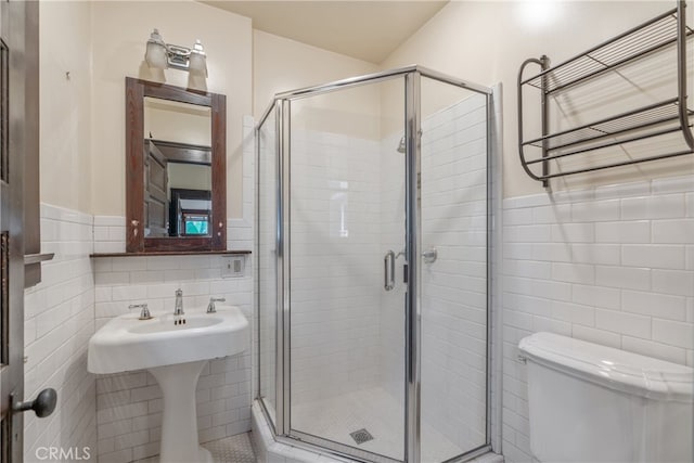 2280 W 24th St, Los Angeles, CA 90018 - bathroom featuring a stall shower, toilet, tile walls, and a wainscoted wall