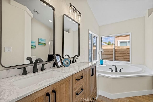bathroom featuring a sink, lofted ceiling, visible vents, and a bath