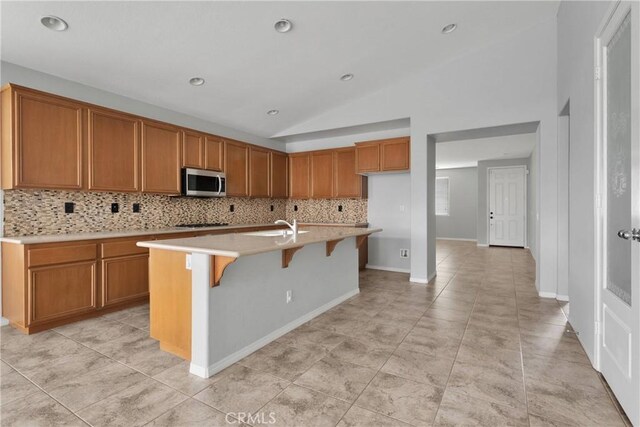 13204 Monrovia St, Hesperia, CA 92344 - kitchen with stainless steel microwave, light countertops, backsplash, and brown cabinets