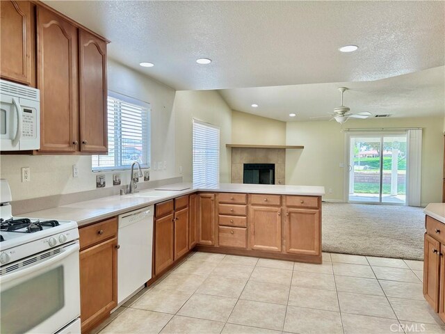 27813 Hummingbird Ln, Helendale, CA 92342 - kitchen with open floor plan, white appliances, a sink, a tiled fireplace, and a peninsula