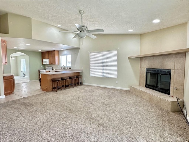 27813 Hummingbird Ln, Helendale, CA 92342 - living room with vaulted ceiling, recessed lighting, light colored carpet, ceiling fan, and a tiled fireplace
