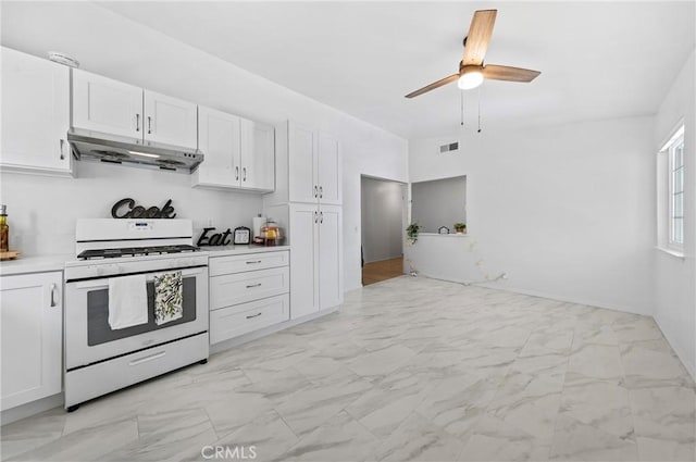 kitchen featuring white cabinets, a ceiling fan, under cabinet range hood, white gas stove, and marble finish floor