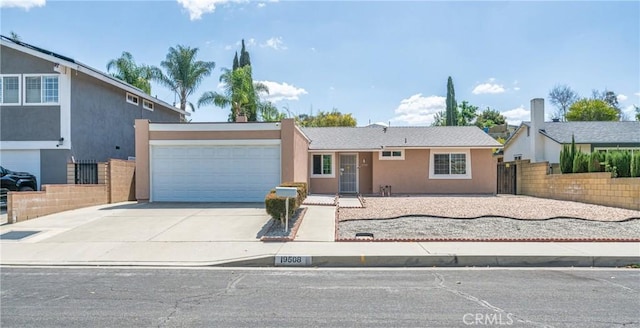 view of front of home with driveway, stucco siding, fence, and an attached garage