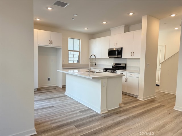 15903 Blue Copper Way, Fontana, CA 92336 - kitchen featuring appliances with stainless steel finishes, light wood-style floors, white cabinetry, an island with sink, and light countertops