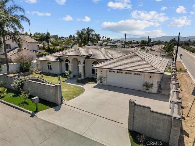 1403 Sonora St, San Bernardino, CA 92404 - mediterranean / spanish home featuring an attached garage, stucco siding, a tile roof, a fenced front yard, and driveway