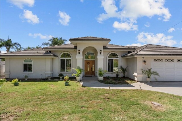 1403 Sonora St, San Bernardino, CA 92404 - mediterranean / spanish home with a tile roof, a front yard, concrete driveway, stucco siding, and a garage