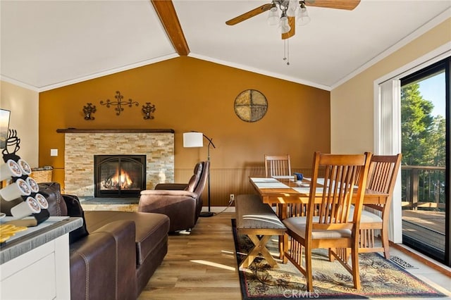 interior space with lofted ceiling with beams, a wainscoted wall, ceiling fan, ornamental molding, and light wood-type flooring