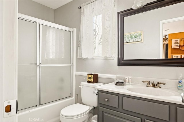 bathroom featuring toilet, shower / bath combination with glass door, and vanity