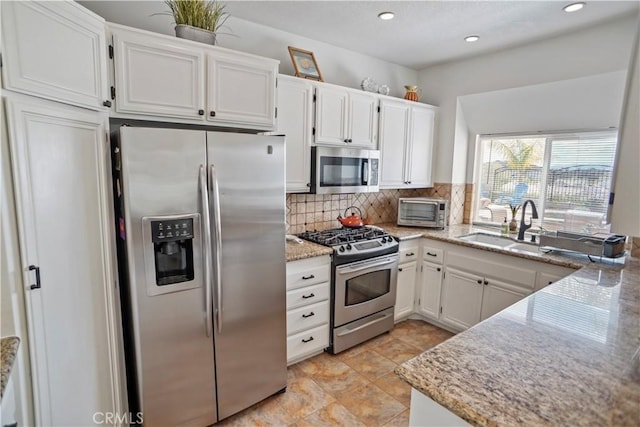 kitchen featuring light stone countertops, white cabinetry, backsplash, and appliances with stainless steel finishes