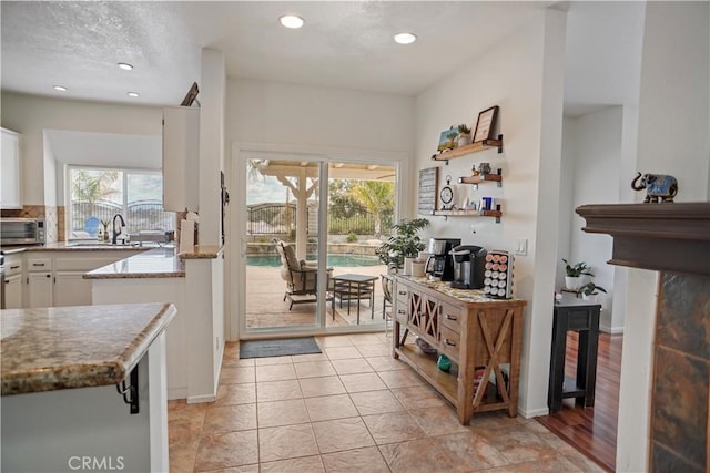 interior space featuring light stone countertops, open shelves, white cabinets, recessed lighting, and a toaster