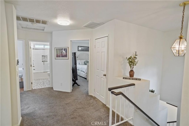 hall featuring visible vents, baseboards, and carpet flooring