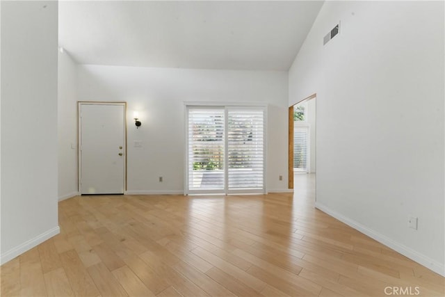 8292 Manifesto Cir, Huntington Beach, CA 92646 - empty room featuring light wood-style floors, baseboards, visible vents, and a towering ceiling