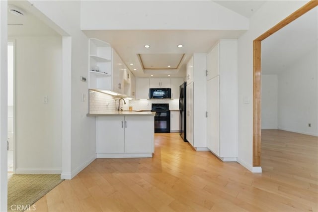 8292 Manifesto Cir, Huntington Beach, CA 92646 - kitchen with tasteful backsplash, a peninsula, light wood-style floors, white cabinetry, and black appliances