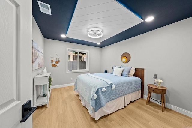 bedroom featuring baseboards, visible vents, and wood finished floors