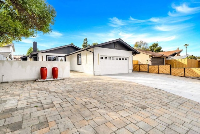 ranch-style house with stucco siding, fence, an attached garage, decorative driveway, and a gate