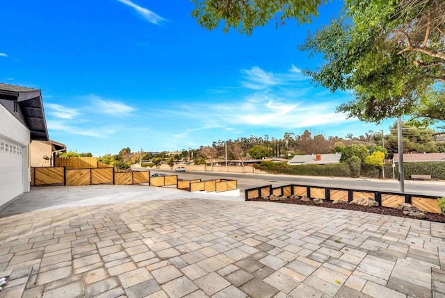 view of patio featuring a gate, a garage, and fence