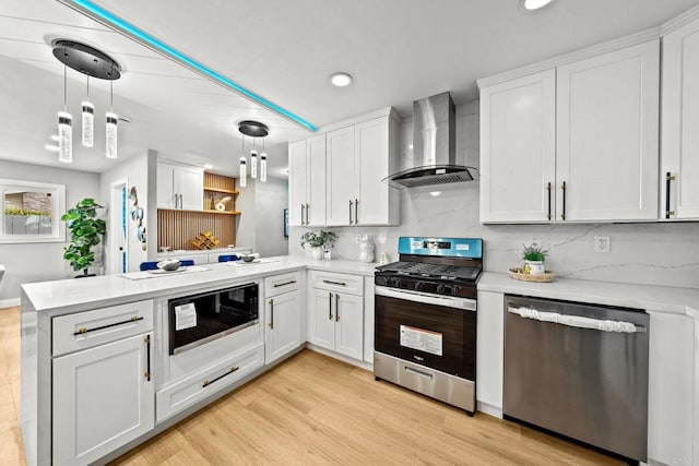 kitchen featuring wall chimney range hood, light countertops, a peninsula, and stainless steel appliances