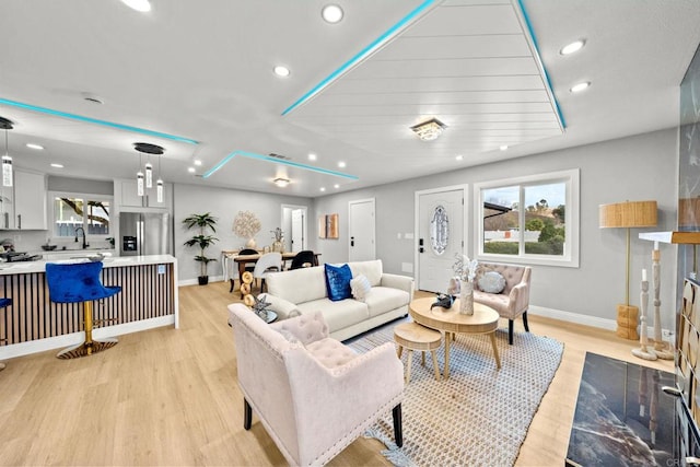 living area with baseboards, visible vents, light wood-style flooring, and recessed lighting
