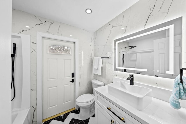 bathroom featuring stone wall, toilet, vanity, and tile walls