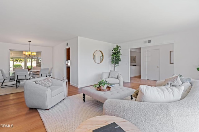 living room featuring baseboards, visible vents, a notable chandelier, and wood finished floors