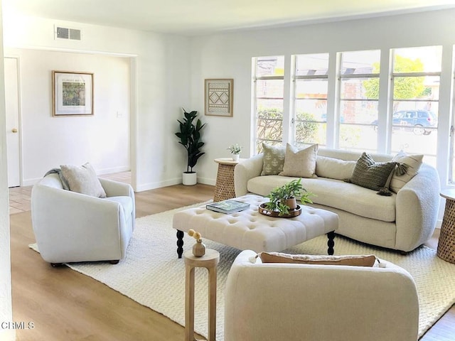 living room featuring baseboards, visible vents, and wood finished floors