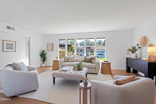 living area with baseboards, visible vents, and wood finished floors