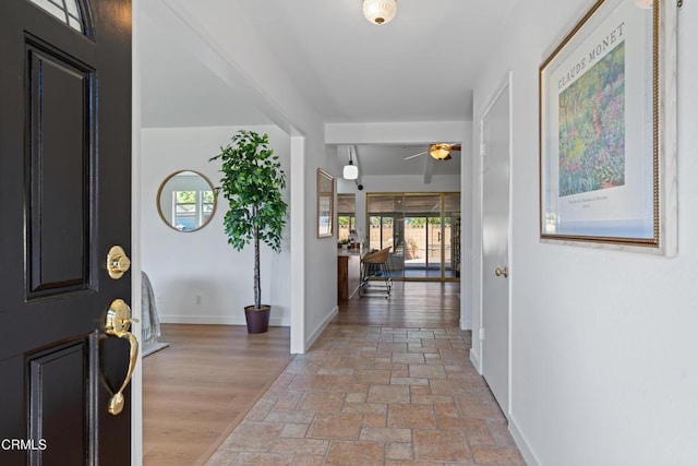 entryway featuring baseboards, light wood-style flooring, and a ceiling fan