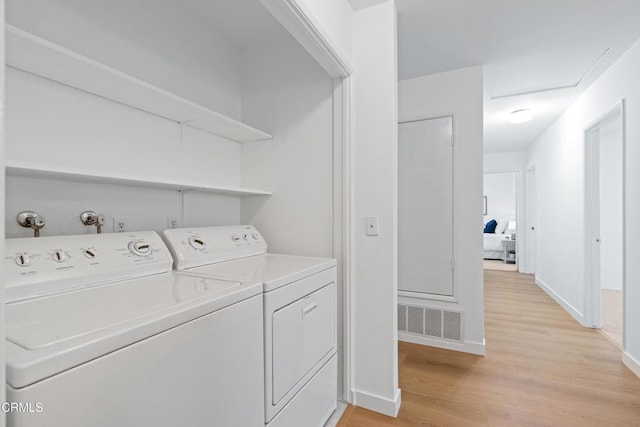 washroom featuring visible vents, independent washer and dryer, baseboards, laundry area, and light wood-style floors