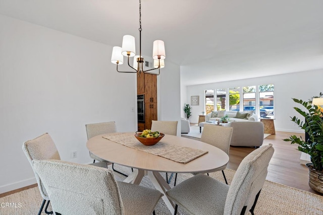 dining space with baseboards, a notable chandelier, and light wood-style floors