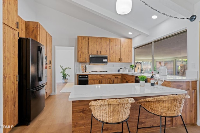 kitchen with lofted ceiling with beams, light countertops, a sink, light wood-style floors, and black appliances