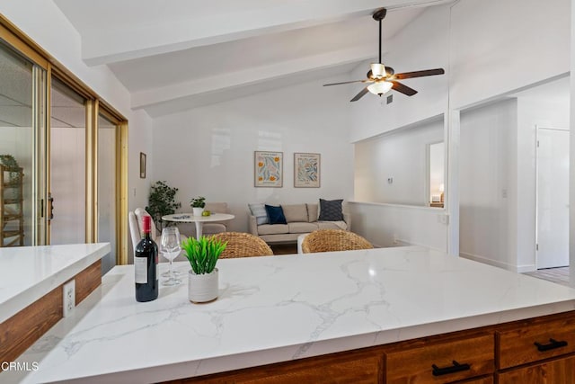 interior space with vaulted ceiling with beams, light stone countertops, brown cabinets, open floor plan, and ceiling fan