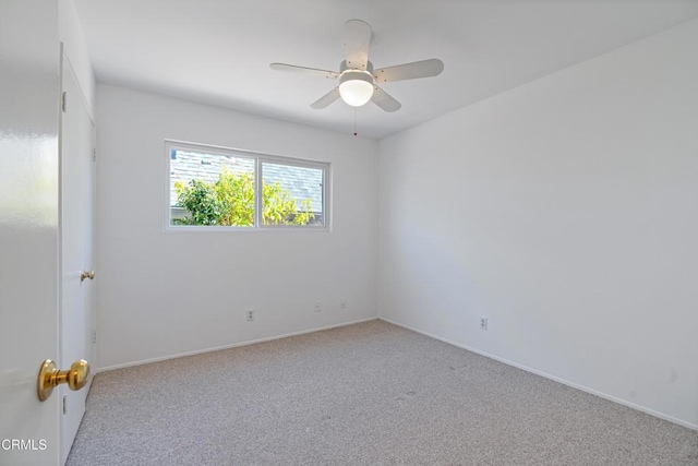 carpeted empty room with a ceiling fan and baseboards
