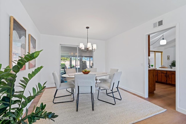 dining room with baseboards, visible vents, wood finished floors, and a chandelier