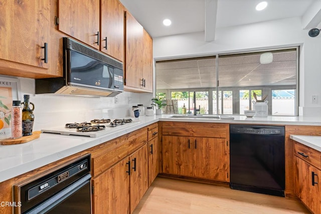 kitchen featuring light countertops, black appliances, light wood-type flooring, and plenty of natural light