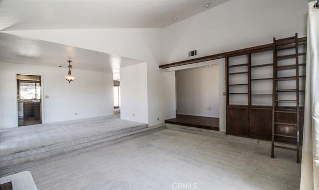 unfurnished living room featuring carpet, visible vents, and vaulted ceiling