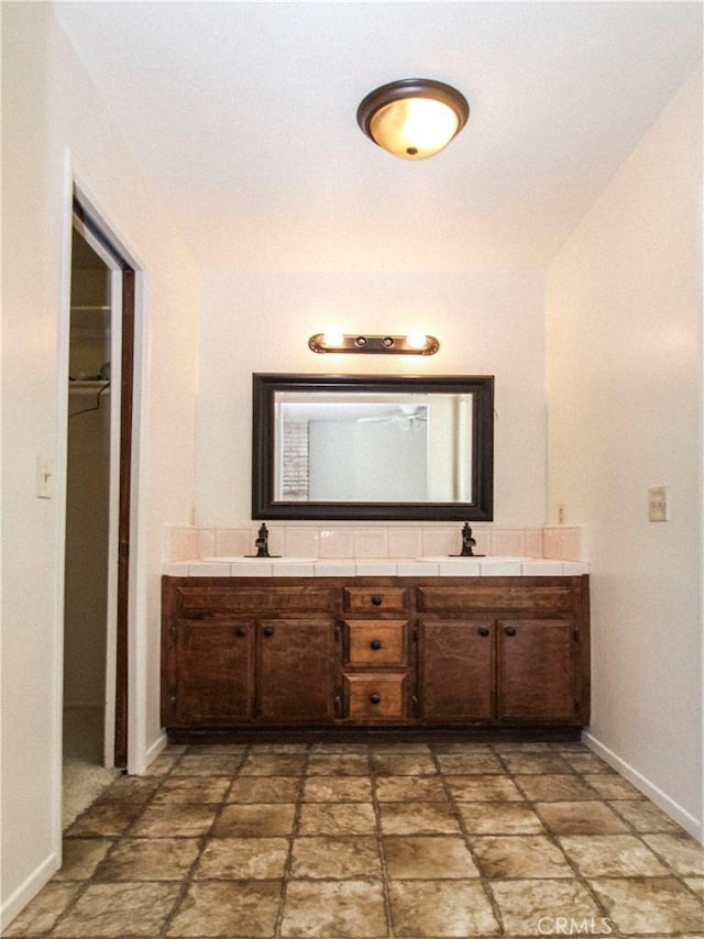 full bath with double vanity and baseboards