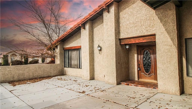 exterior space with stucco siding and a patio area