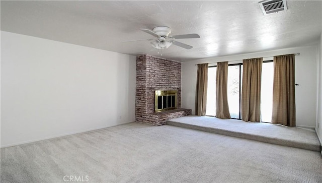 unfurnished living room with a fireplace, a ceiling fan, visible vents, a textured ceiling, and carpet floors